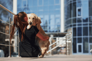 lady holding a dog on the steps in front of a tall building