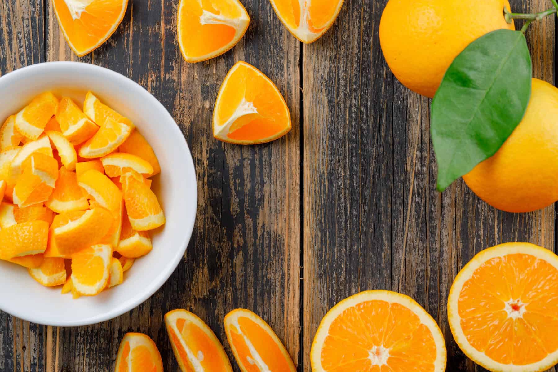 can guinea pigs eat oranges - sliced oranges on a wood table with some smaller pieces in a white bowl