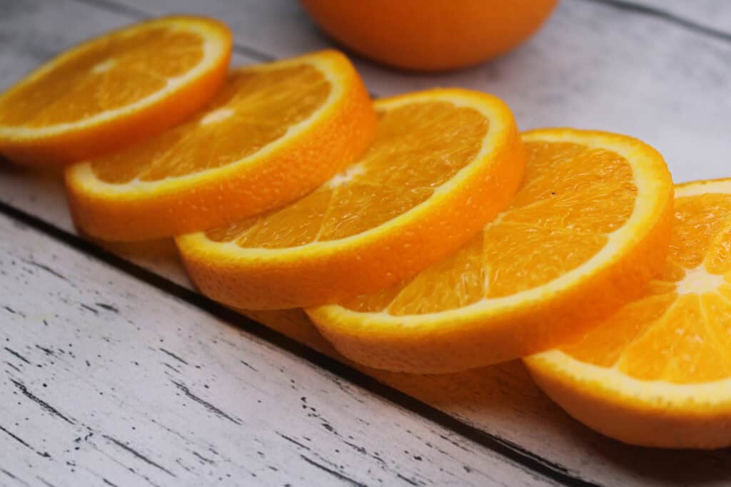 Slices of orange stacked on top of each other on a wooden table - can guinea pigs eat oranges