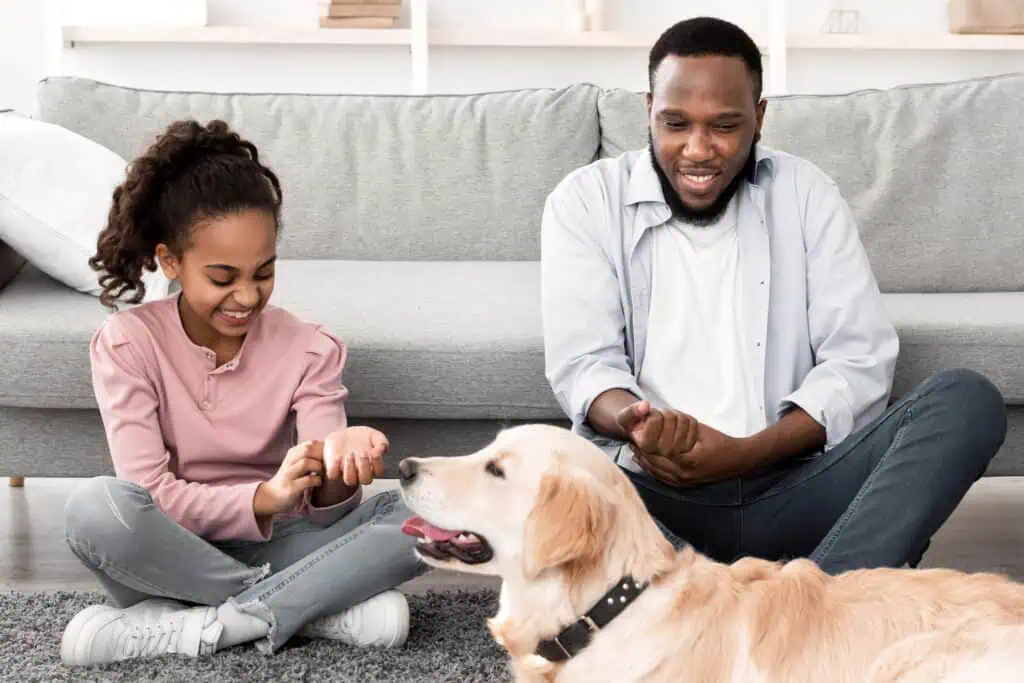 A man and young lady with a yellow lab sitting on the floor